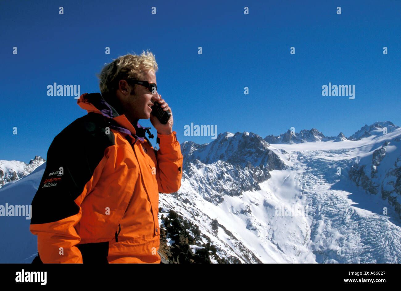 Skifahrer mit Handy auf Berggipfel in den französischen Alpen nahe der Grenze mit der Schweiz Stockfoto