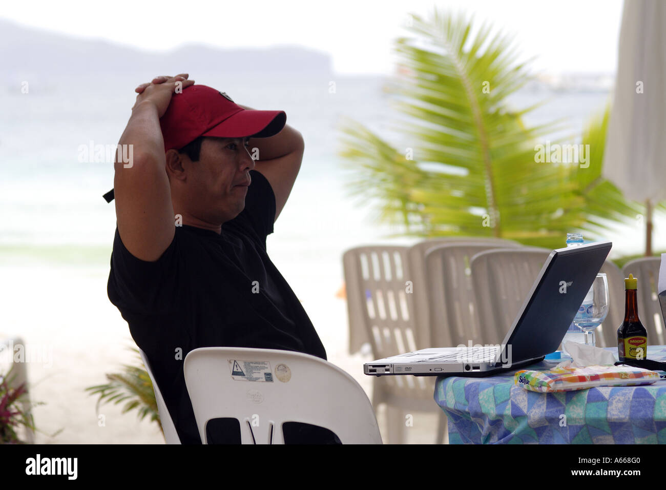 Philippinischen Mann aus Manilla an seinem Laptopcomputer arbeiten Urlaub in Boracay, Philippinen Stockfoto