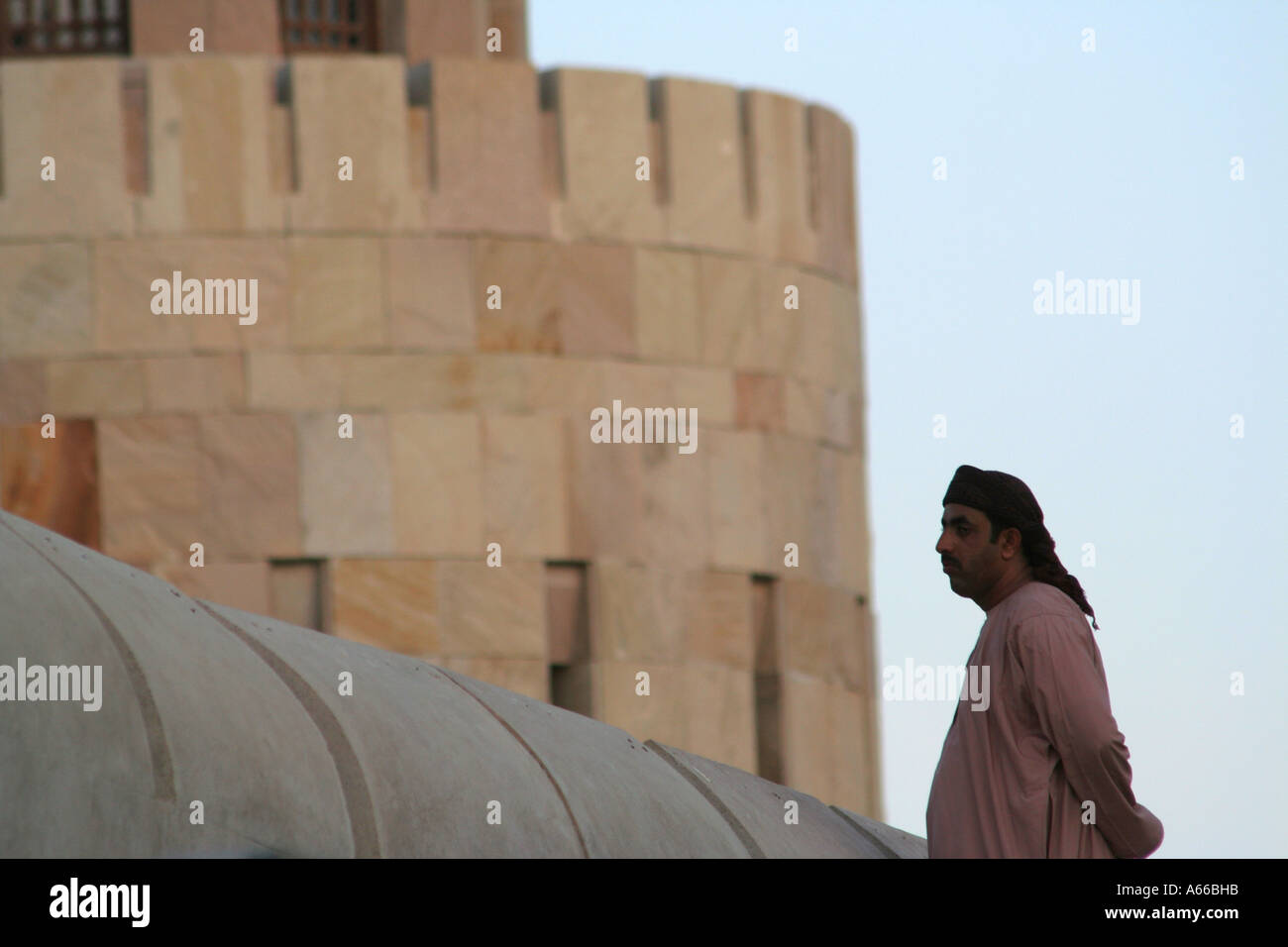 Muscat Oman, arabischer Mann mit Turban steht auf der Stadtmauer mit Blick auf Hafen von Muscat Stockfoto