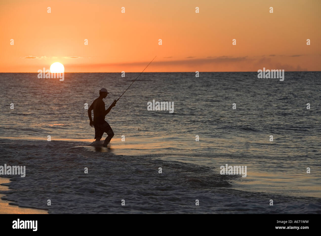 Ein Fischer watet in die Brandung als die Sonne untergeht auf Fraser Island Stockfoto