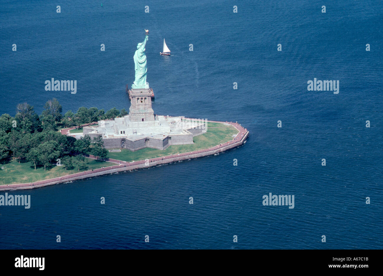 Die legendäre Silhouette von Lady Liberty bleibt ein mächtiges Symbol für Freiheit und Widerstandsfähigkeit vor dem Hintergrund des tiefblauen Atlantiks. Stockfoto