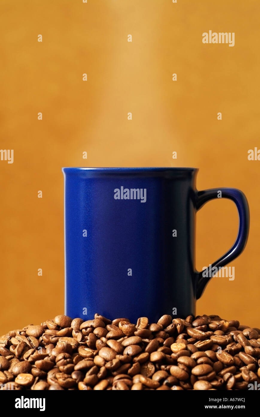 Dampfende Tasse Kaffee auf einem Haufen von Kaffeebohnen Stockfoto