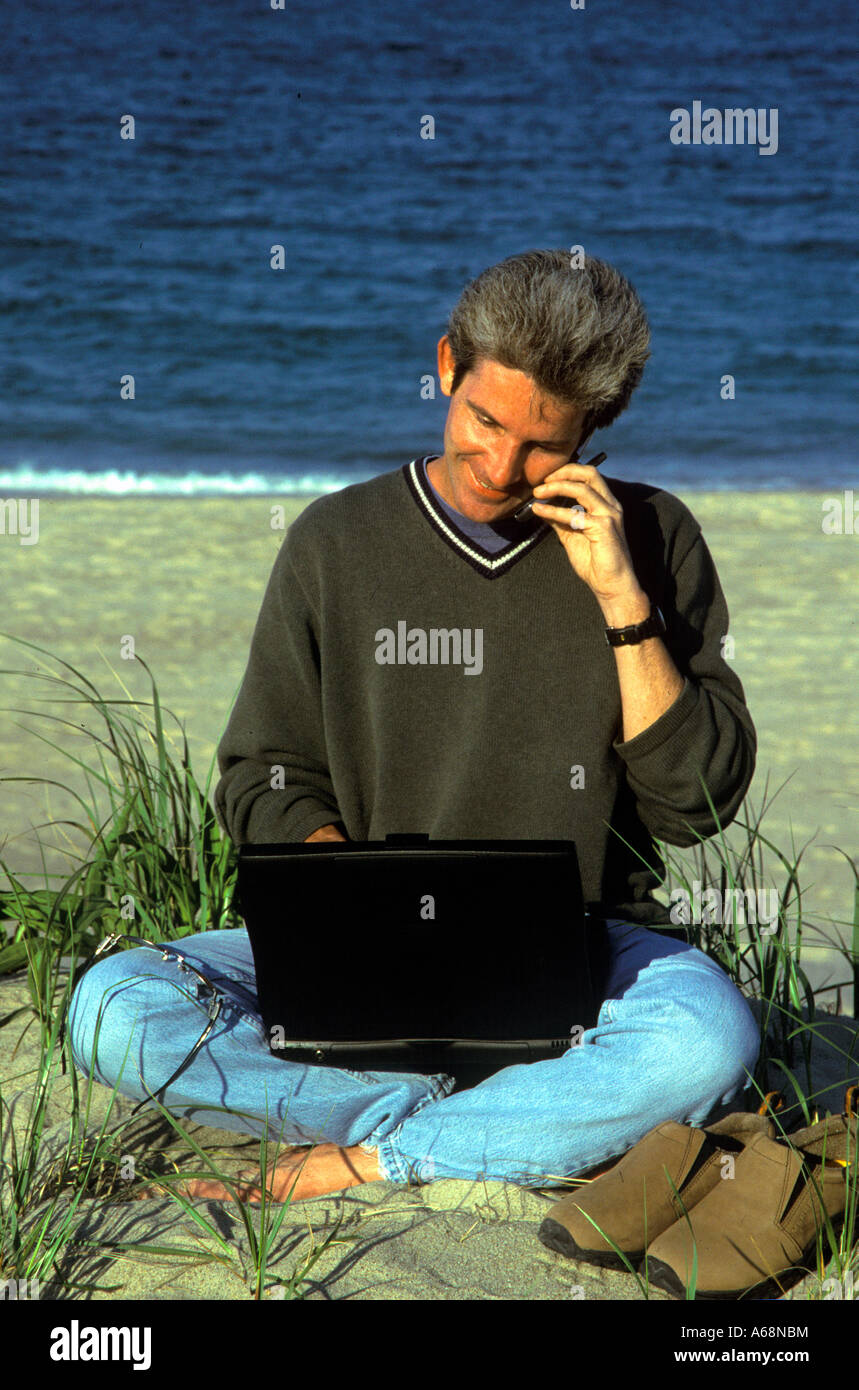 Man arbeitet an einem Laptop-Computer, während am Strand Stockfoto