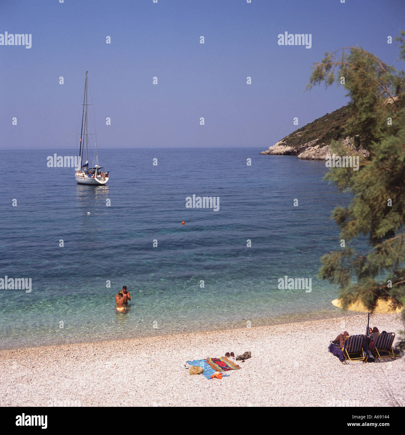 Paar am Makris Gialos Beach & Bucht mit Segelyacht im Meer vor Anker vor der Küste von Zakynthos Insel der griechischen Inseln Griechenland Stockfoto