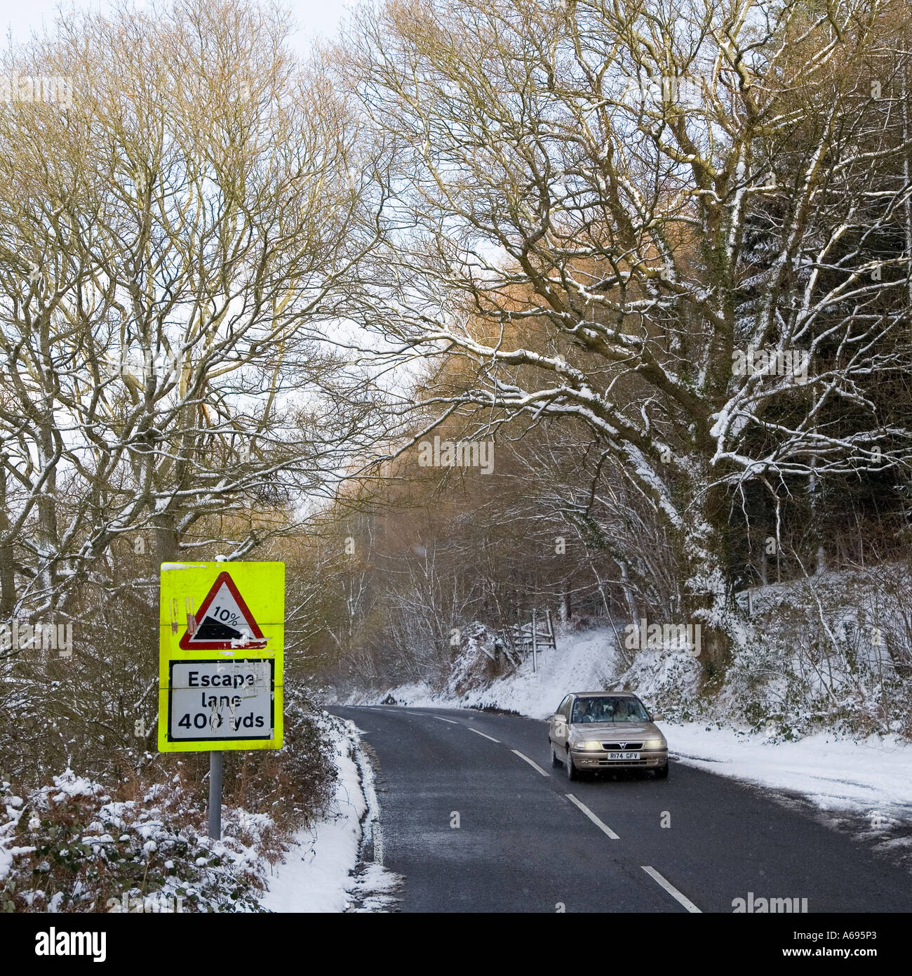 Auto mit Scheinwerfern auf der Fahrt bergauf unter winterlichen Bedingungen mit Escape Lane Warnschild Wales UK Stockfoto