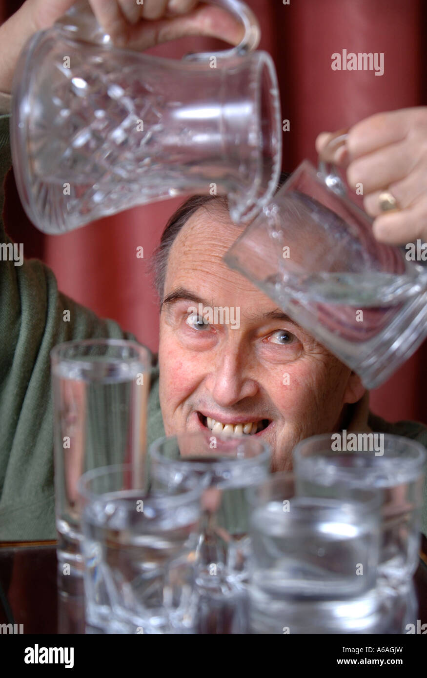 EIN PENSIONIERTER MANN, GIEßEN EIN GLAS WASSER UK Stockfoto