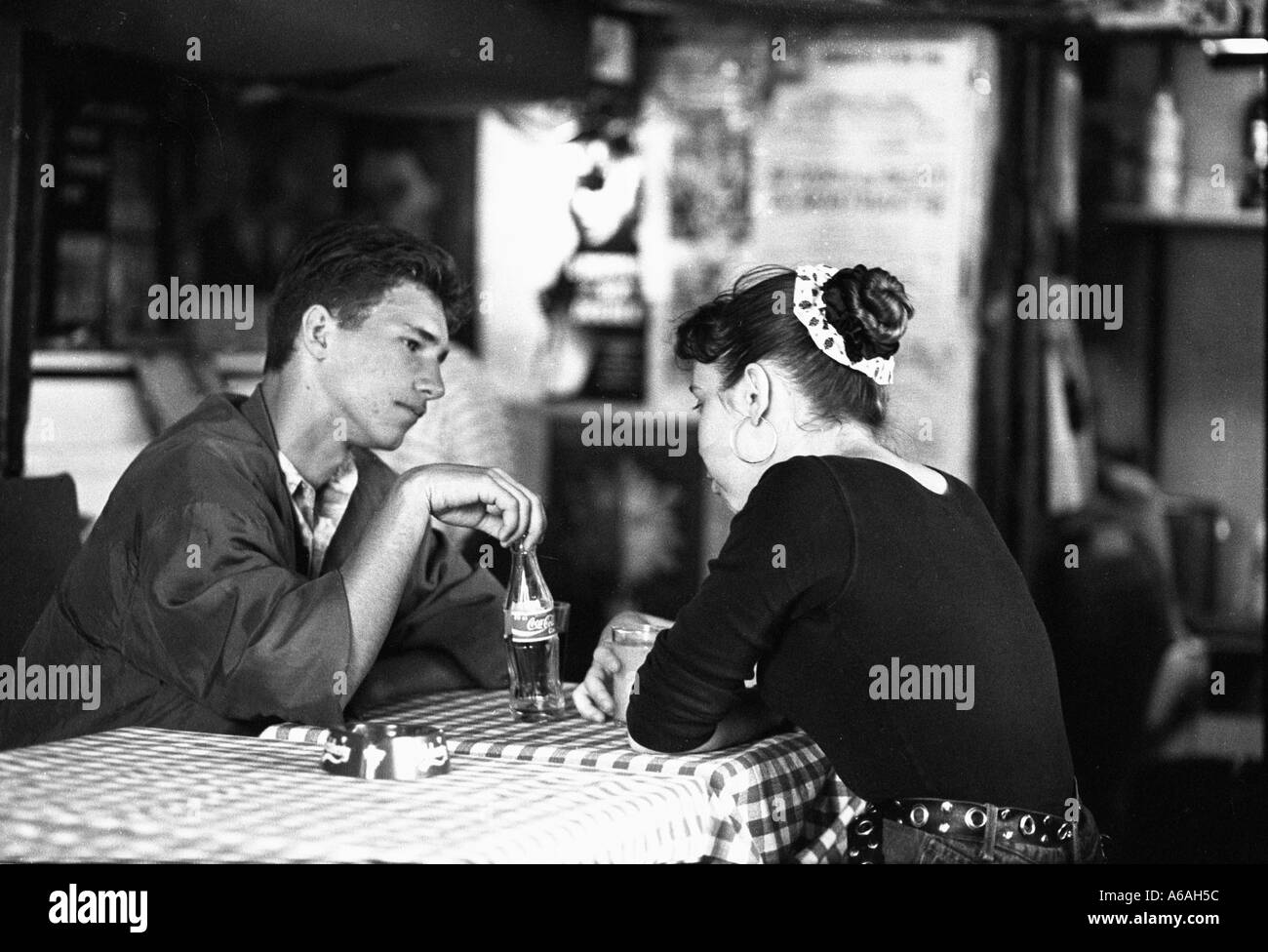 Junge und Mädchen, die in einem Café in Paris, Frankreich. Der junge hält eine Coca-Cola-Flasche. Stockfoto