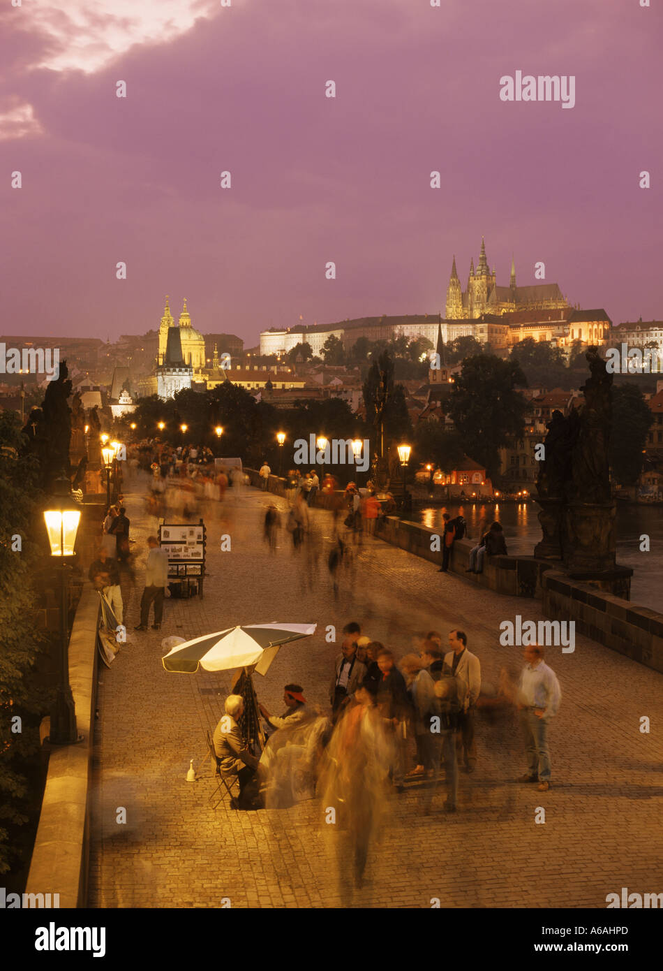 Künstler und Touristen auf der Karlsbrücke unter Straßenlaternen und die Prager Burg bei Nacht Stockfoto