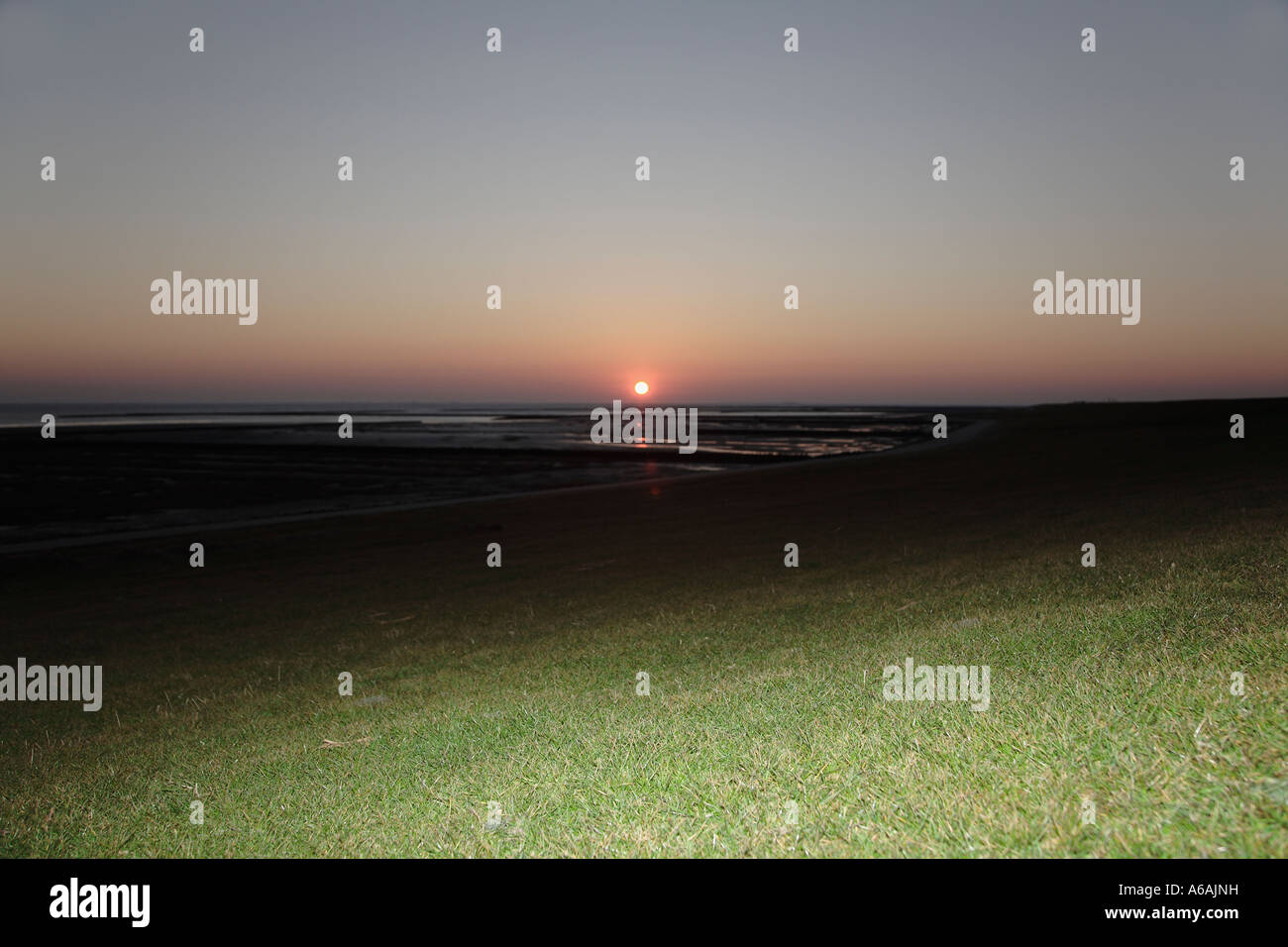 Sonnenuntergang über Rasen bedeckt Damm, Nordsee Küste, Nationalpark Wattenmeer, Friesland, Norddeutschland Stockfoto