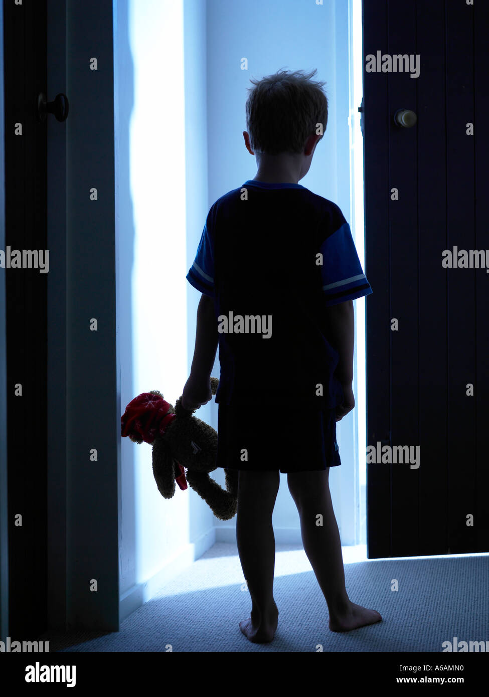 Kind nachts im Haus Richtung ein blaues Licht mit Vorfreude in Pj gekleidet und tragen seine Lieblings teddy Stockfoto