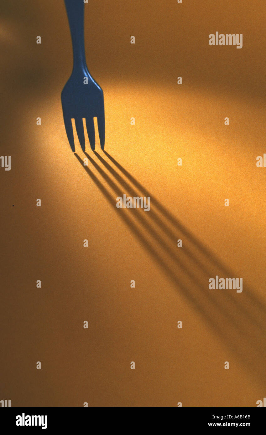eine blaue Gabel stehend auf gelbem Grund Shadown Wirkung Lightspot Kontrast Stockfoto