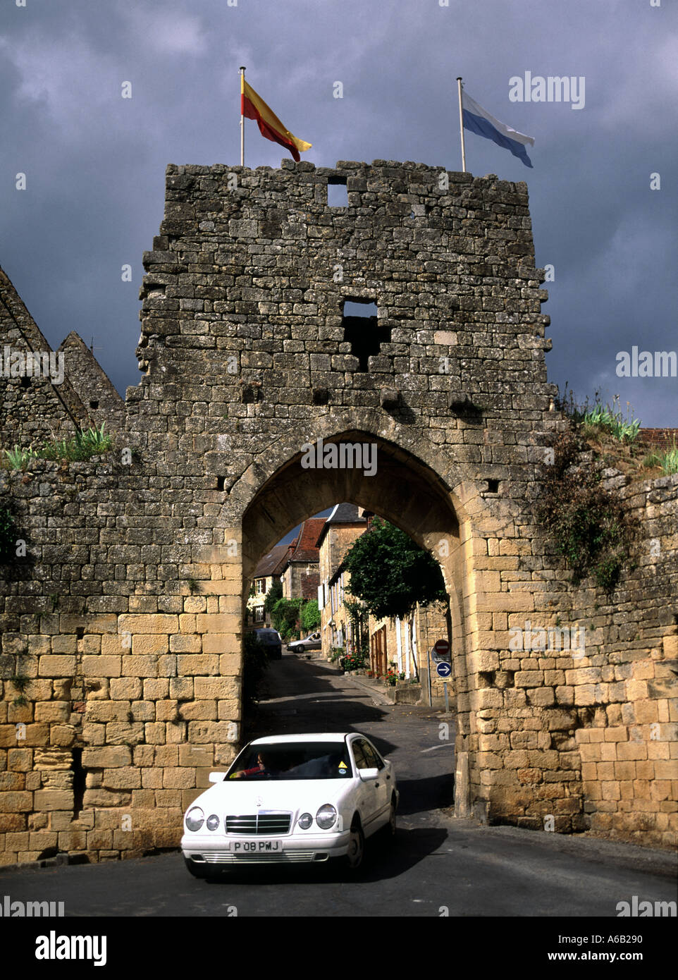 Domme Dordogne Porte Del Bos Car & Stone Gateway Bogenarchiv Straßenszene enge mittelalterliche Straßenflaggen an der historischen Stadtmauer Nouvelle Aquitaine Frankreich Stockfoto