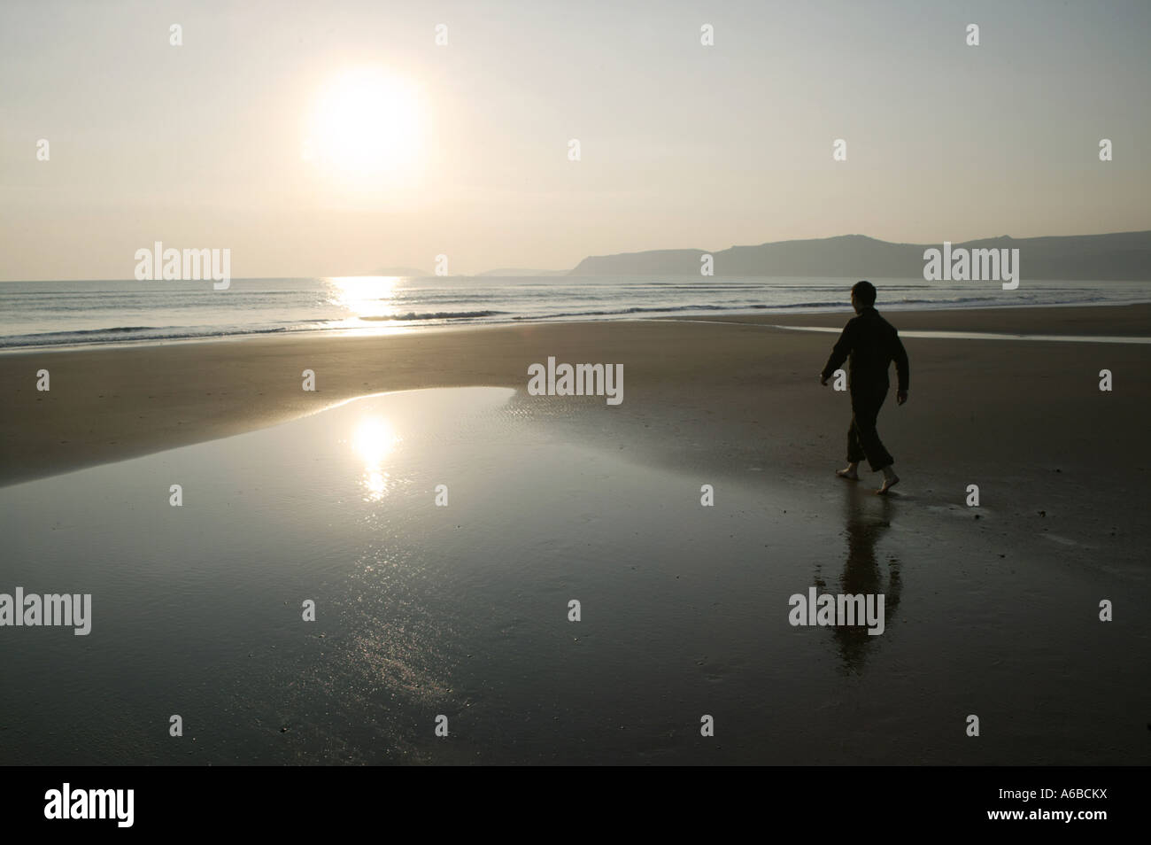 Reflektierender Spaziergang am Strand bei Sonnenuntergang Stockfoto