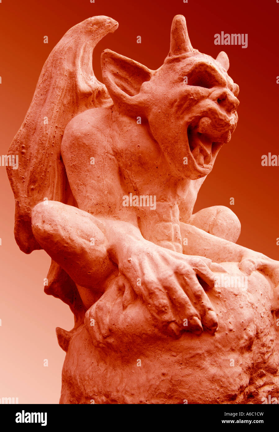 Ein erschreckender, dämonischer steinerner Wasserspeier Grimassen vor einem roten Hintergrund. Stockfoto