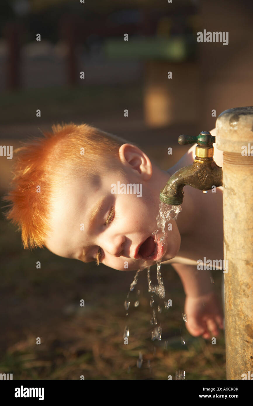 Kleiner Junge aus Wasserhahn trinken Stockfoto