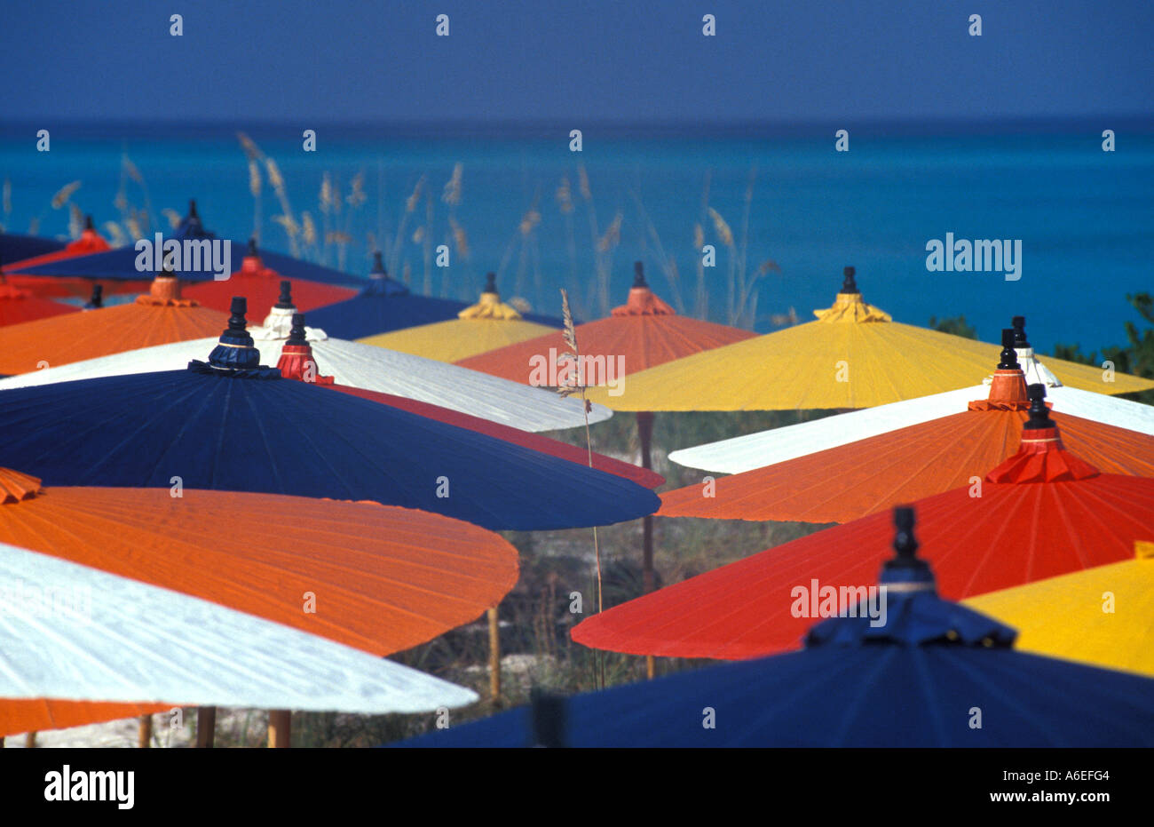Strand Sonnenschirme rot gelb blau weiß orange blau Wasser helle Hintergrundfarben Stockfoto