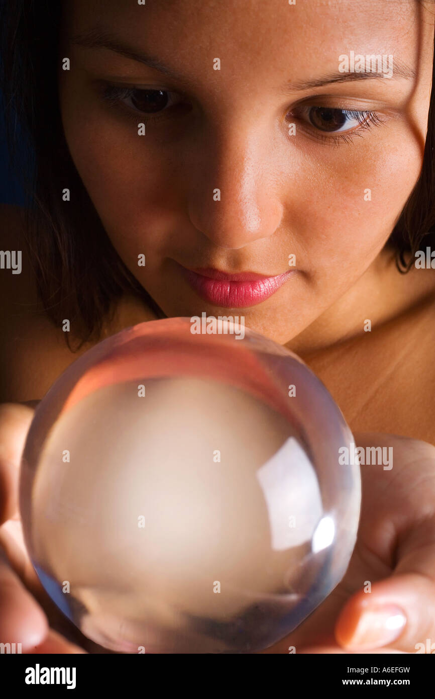Eine junge Frau starrt in eine Kristallkugel Stockfoto