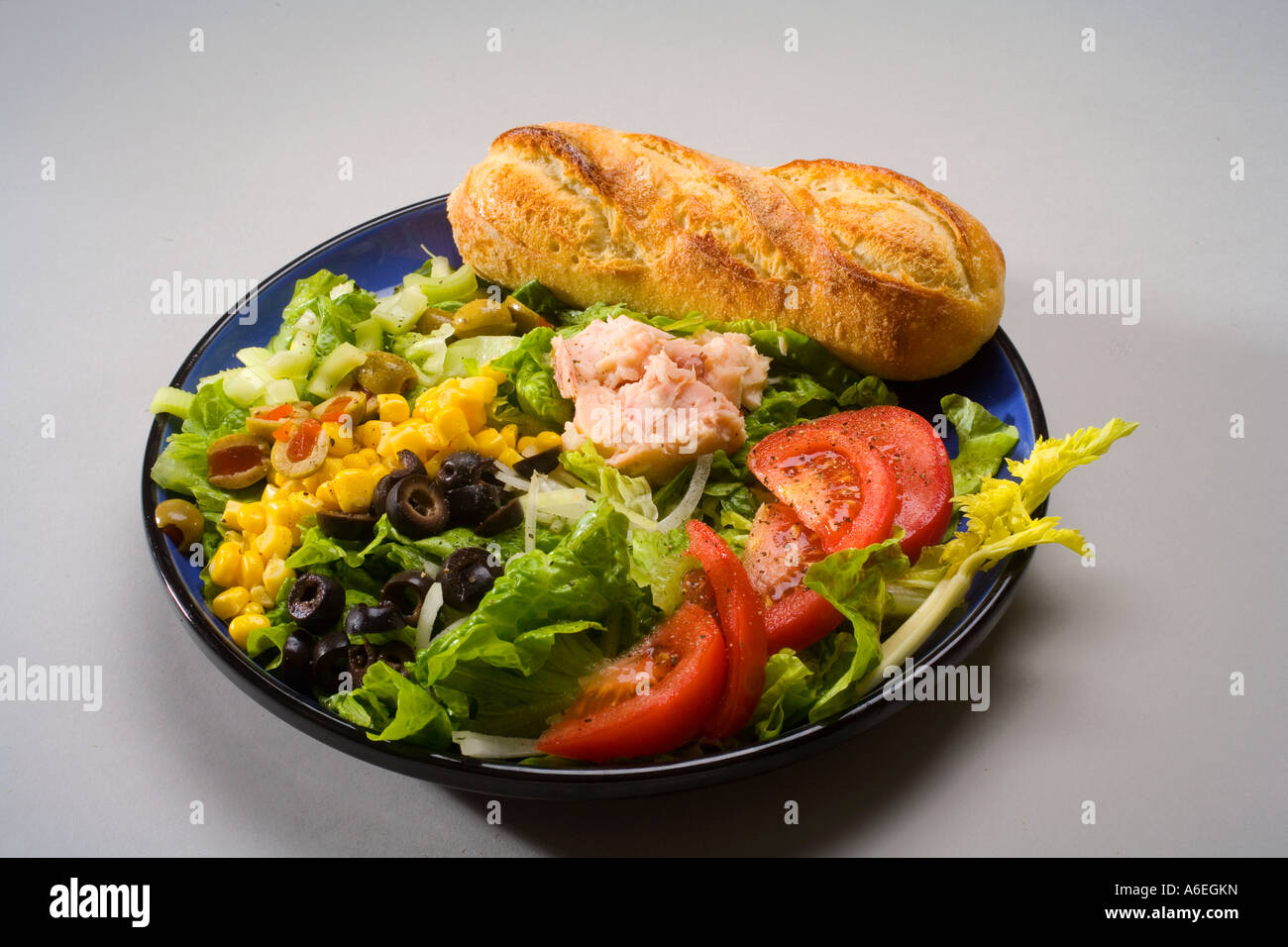 Salat aus Kopfsalat, Tomaten, Thunfisch, Oliven, Mais und Zwiebeln mit einem Laib Brot Französisch Stockfoto