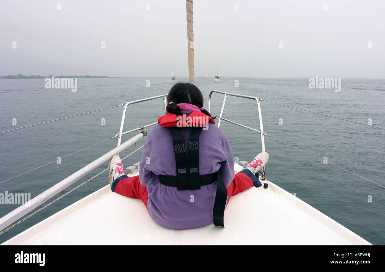 Ein junges Mädchen sitzt im Bug des eine Yacht, The Solent, England Stockfoto