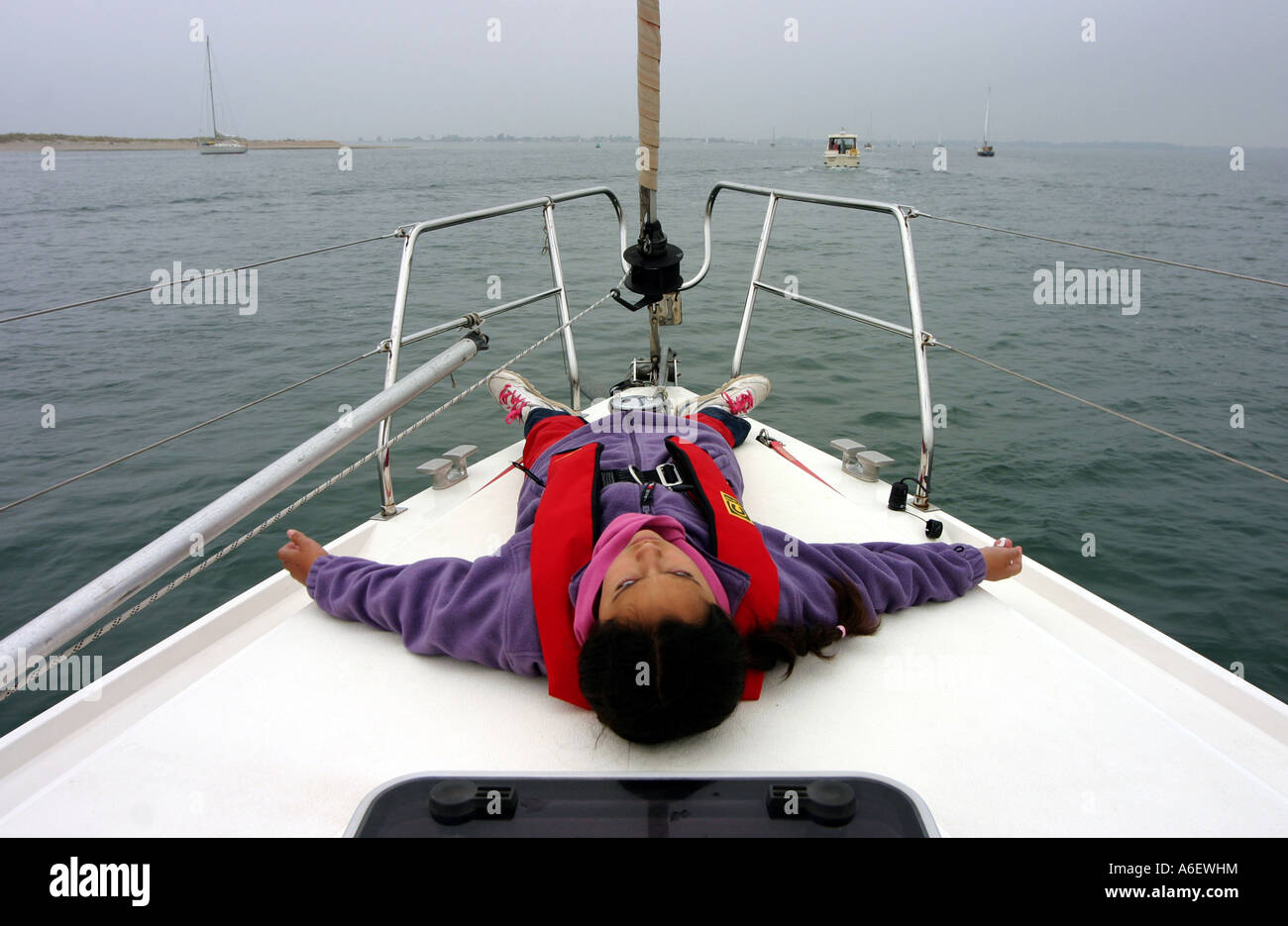Ein junges Mädchen liegt in den Bogen einer Yacht, die Solent, England Stockfoto