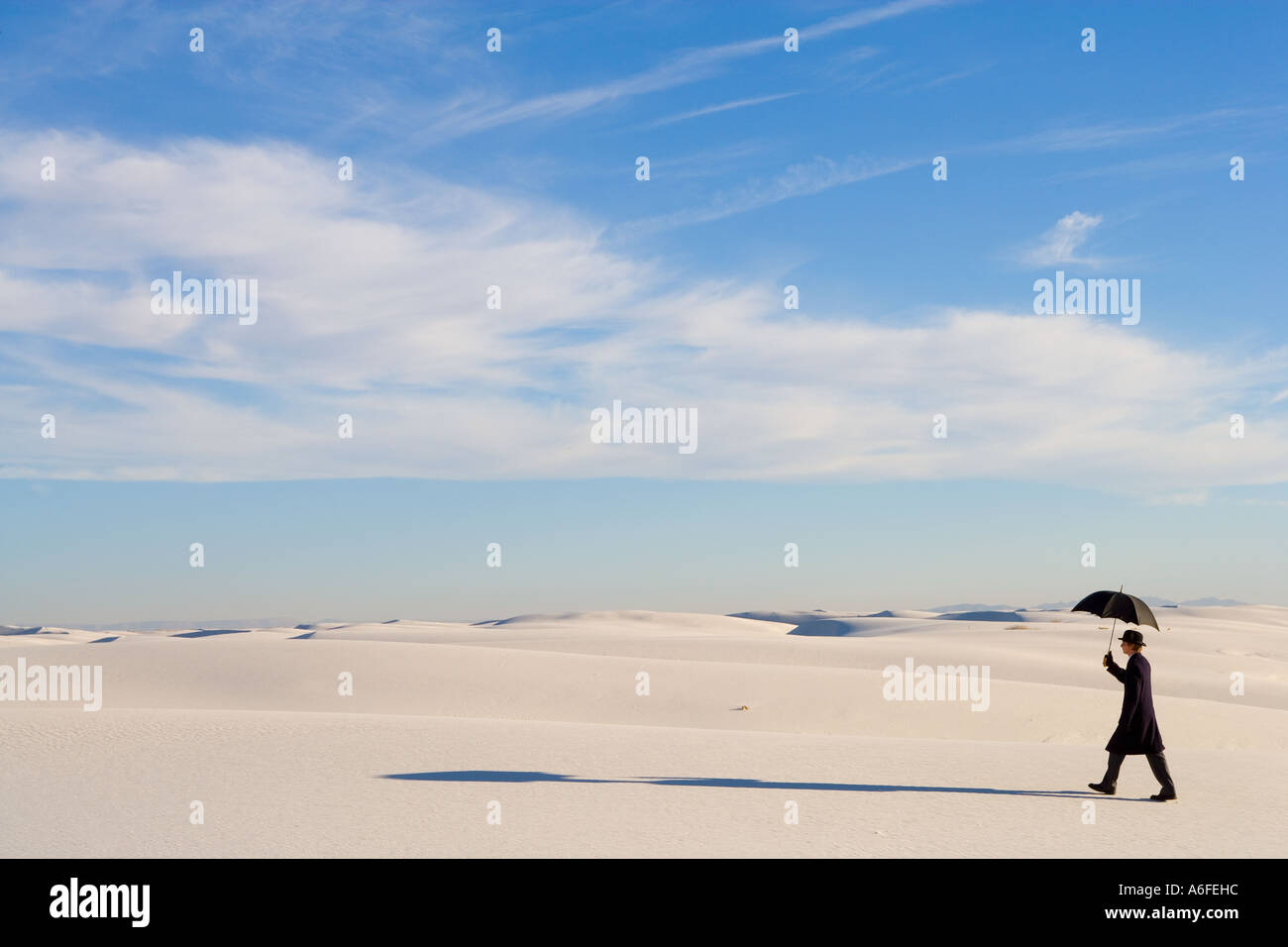 Mann mit Regenschirm im weißen Sand Düne Wüste wandern Stockfoto