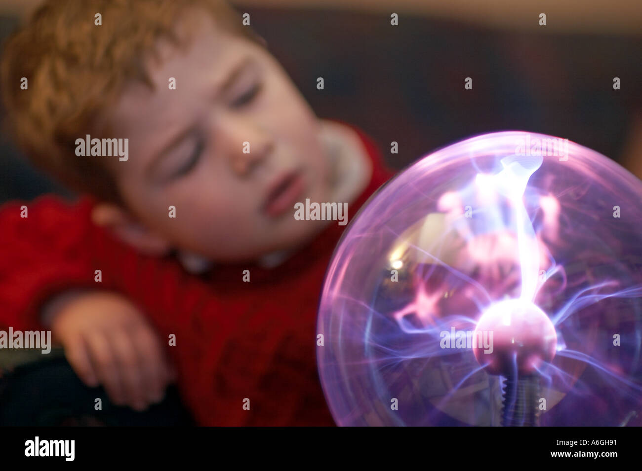 Neugierige neugierige junge Blick auf Plasma Kugel Kugel wissenschaftlichen Spielzeug Stockfoto