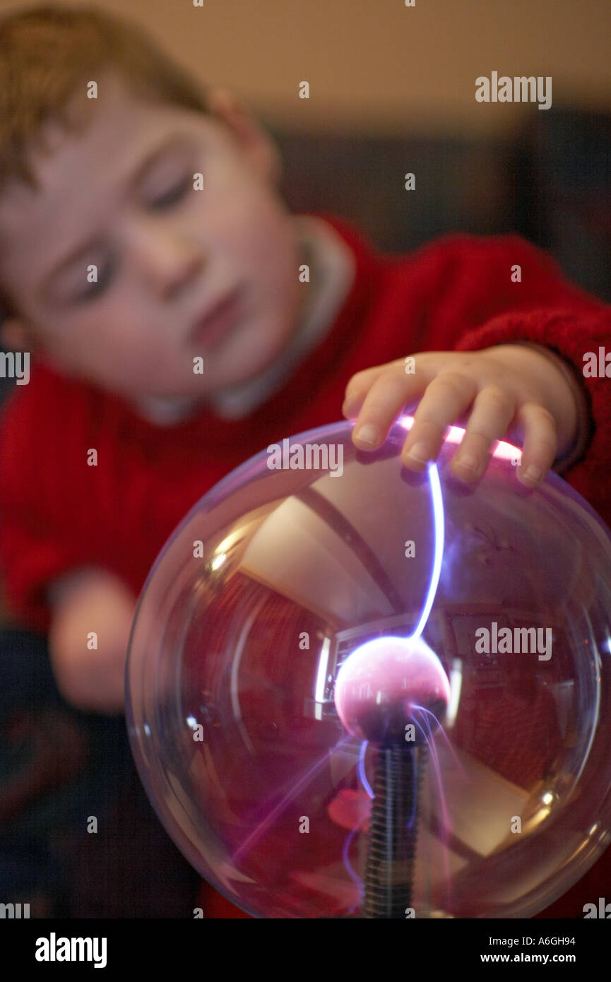 Neugierige neugierige junge betrachten und berühren einen Plasma Kugel Ball wissenschaftlichen Spielzeug Stockfoto