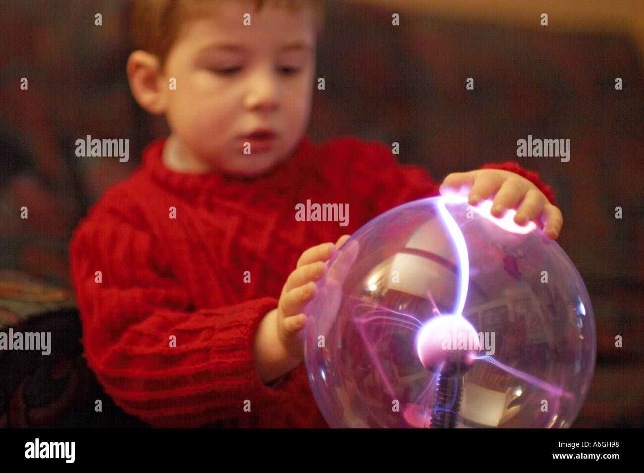 Neugierige neugierige junge betrachten und berühren einen Plasma Kugel Ball wissenschaftlichen Spielzeug Stockfoto