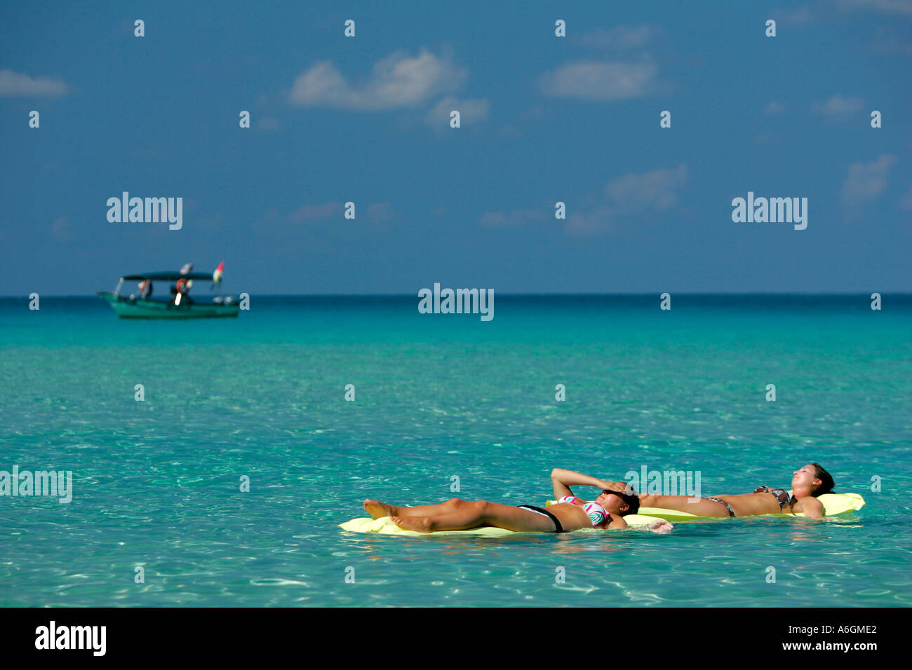 Zwei junge Frau im Bikini schwimmen auf gelben Luftmatratzen Perhentian Kecil Malaysia Stockfoto