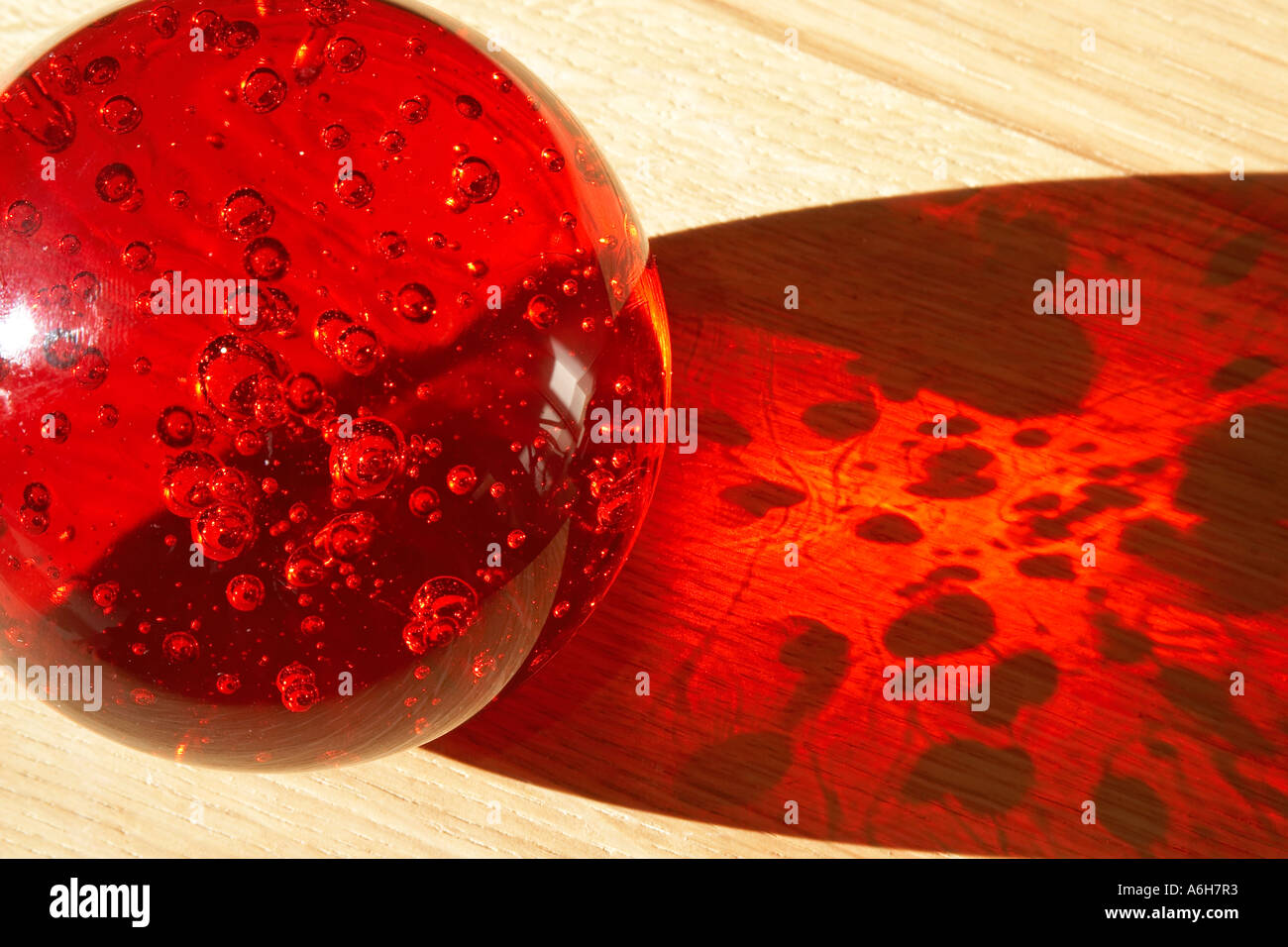 Abstraktes Bild von Sonnenlicht durch rote dekorative Kunst Objekt Glaskugel mit Luftblasen Stockfoto