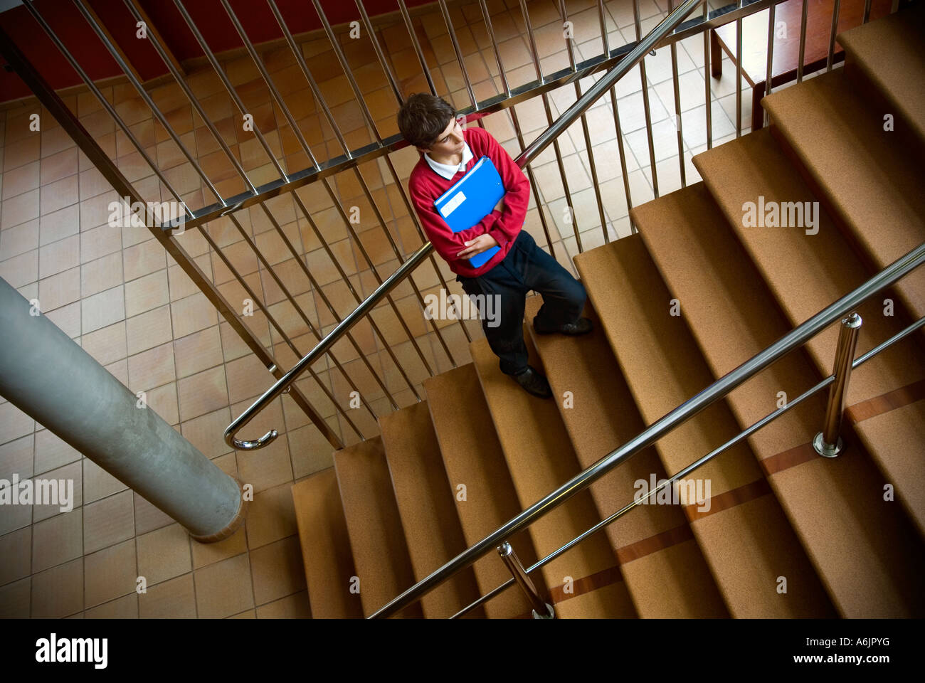 Junior Schuljunge mit Schulklasse studieren Ordner für sich allein im Treppenhaus der Schule Stockfoto