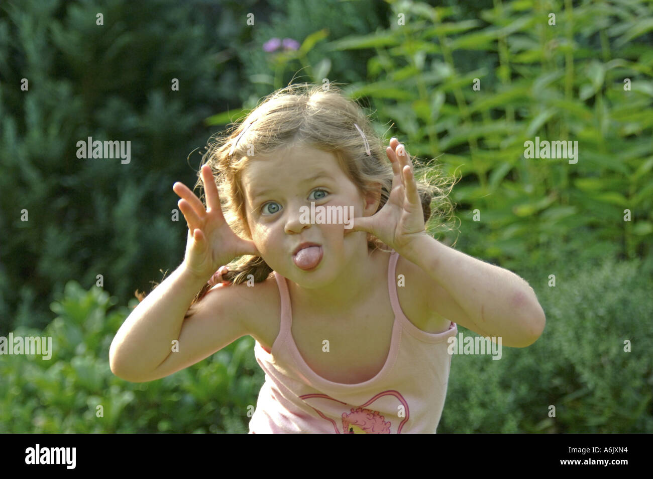 Mädchen macht Grimasse und zeigt ihre Zunge Stockfoto