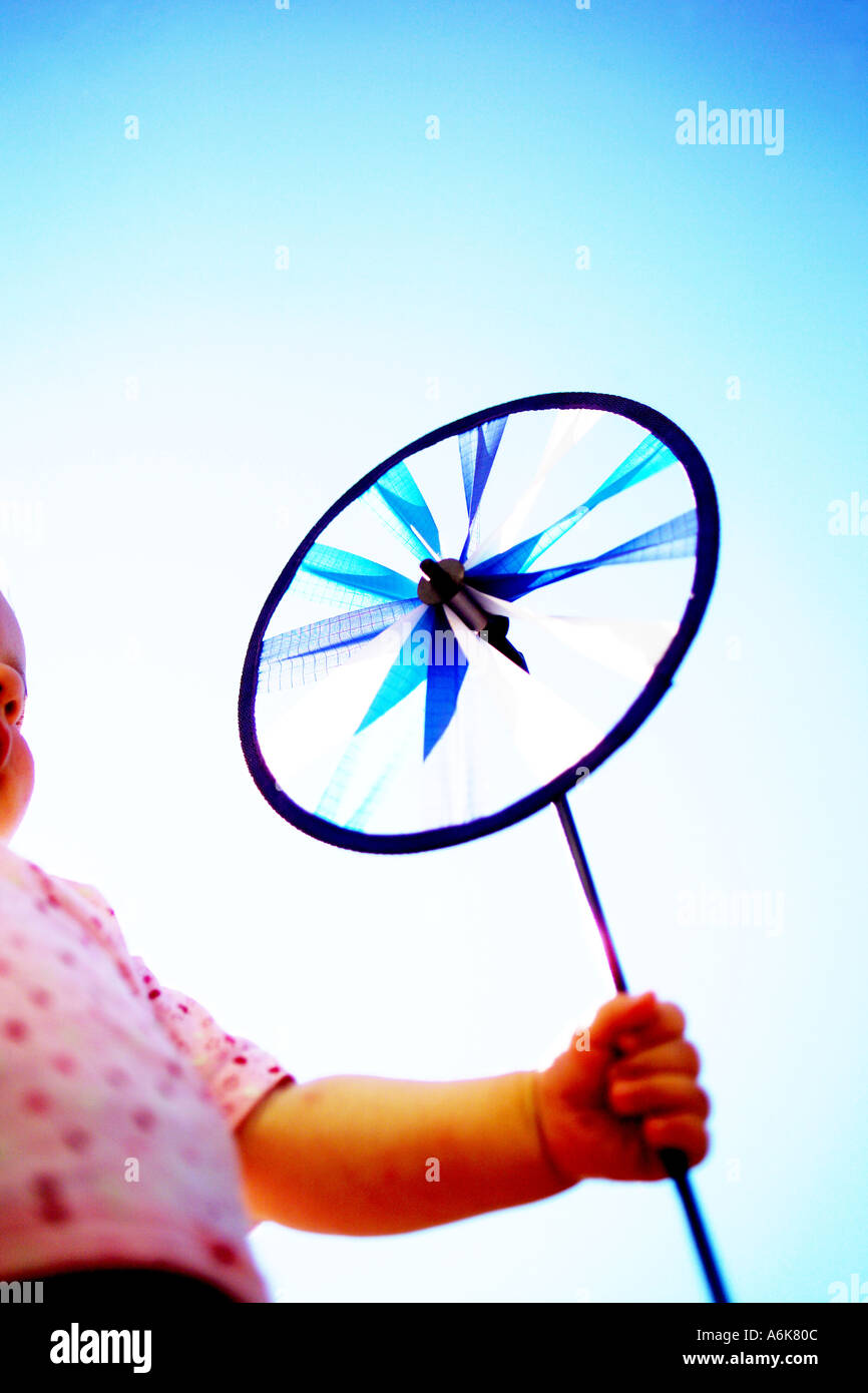 wenig baby hält einen Windwheel in den Himmel Stockfoto