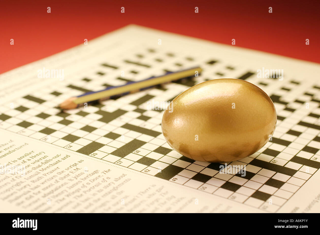 Goldenes Ei und Bleistift auf Kreuzworträtsel Stockfoto