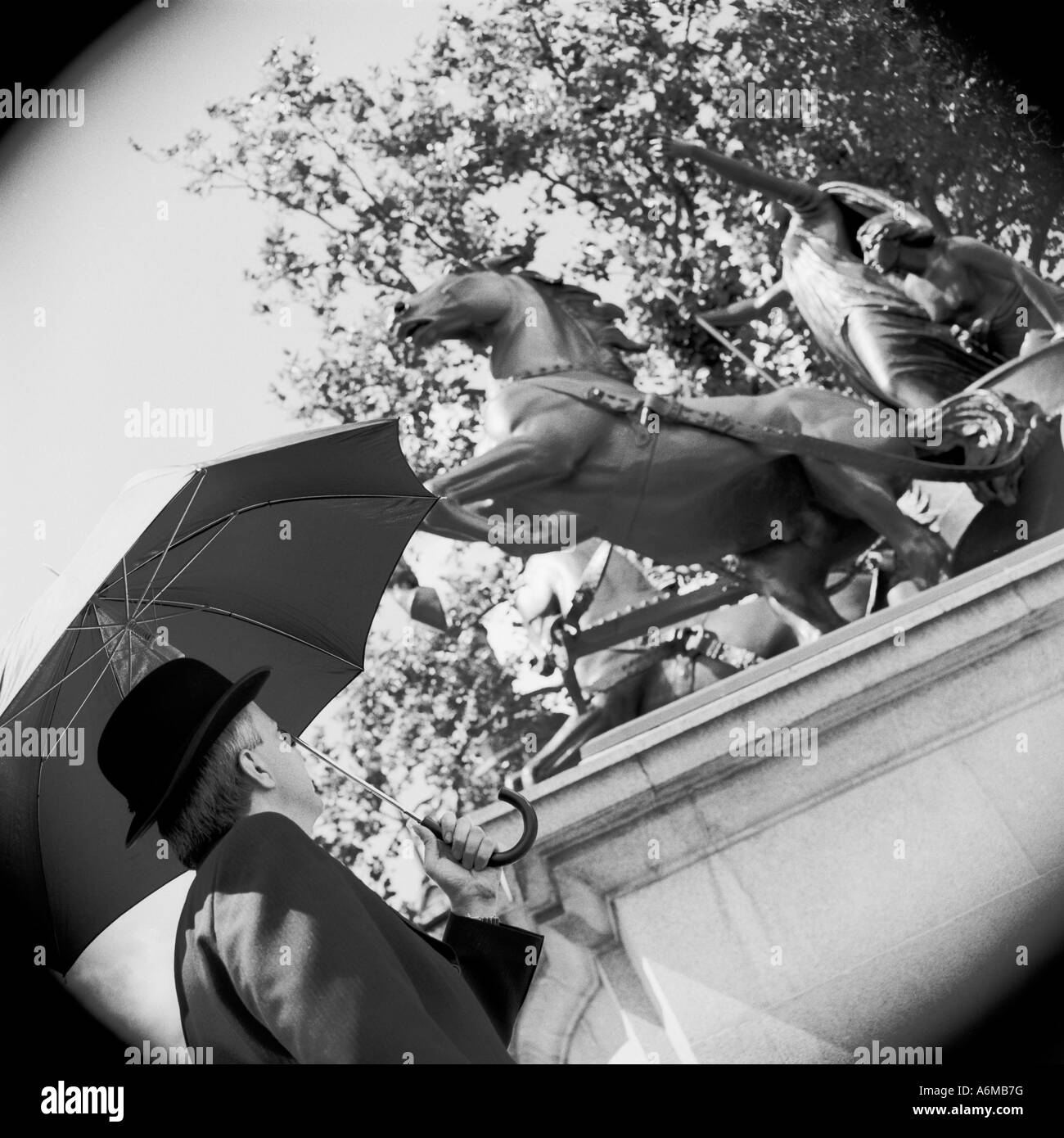 Englischer Stadtgute mit Regenschirm, der zur Statue von Boudicca in Westminster, London aufschaut Stockfoto