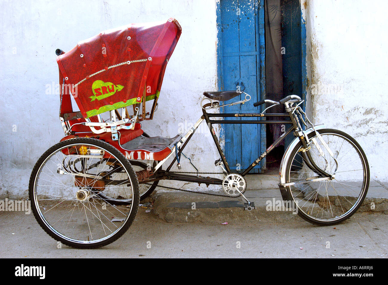 ASB77363 bunte rote Zyklus Rickshaw stand vor blaue Tür im alten Stadt Hyderabad, Andhra Pradesh Indien Stockfoto