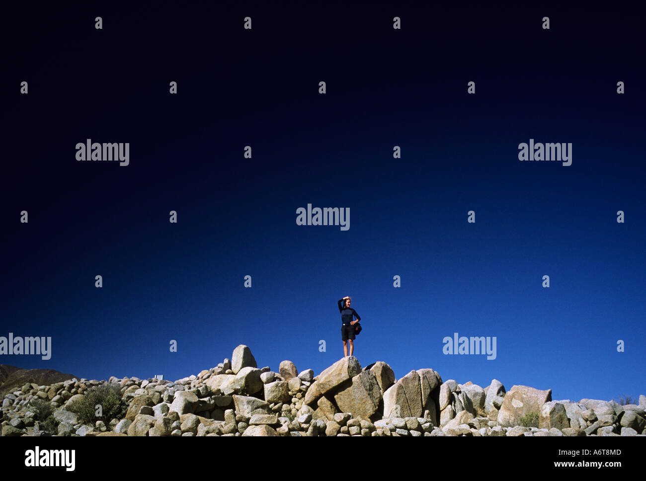 einsame Frau, die auf steinigen Hügel mit tiefblauen Himmel in Argentinien Stockfoto