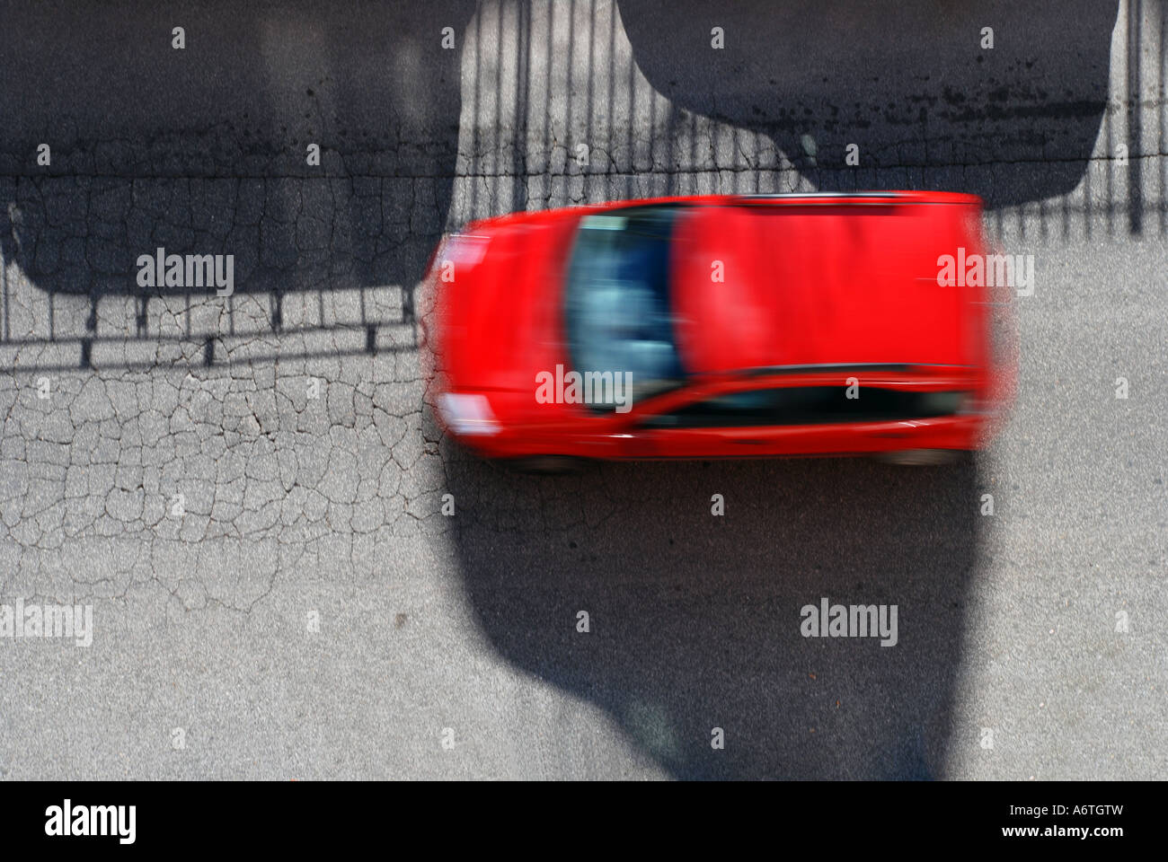 Rotes Auto rennt Weg zwischen den Schatten Stockfoto