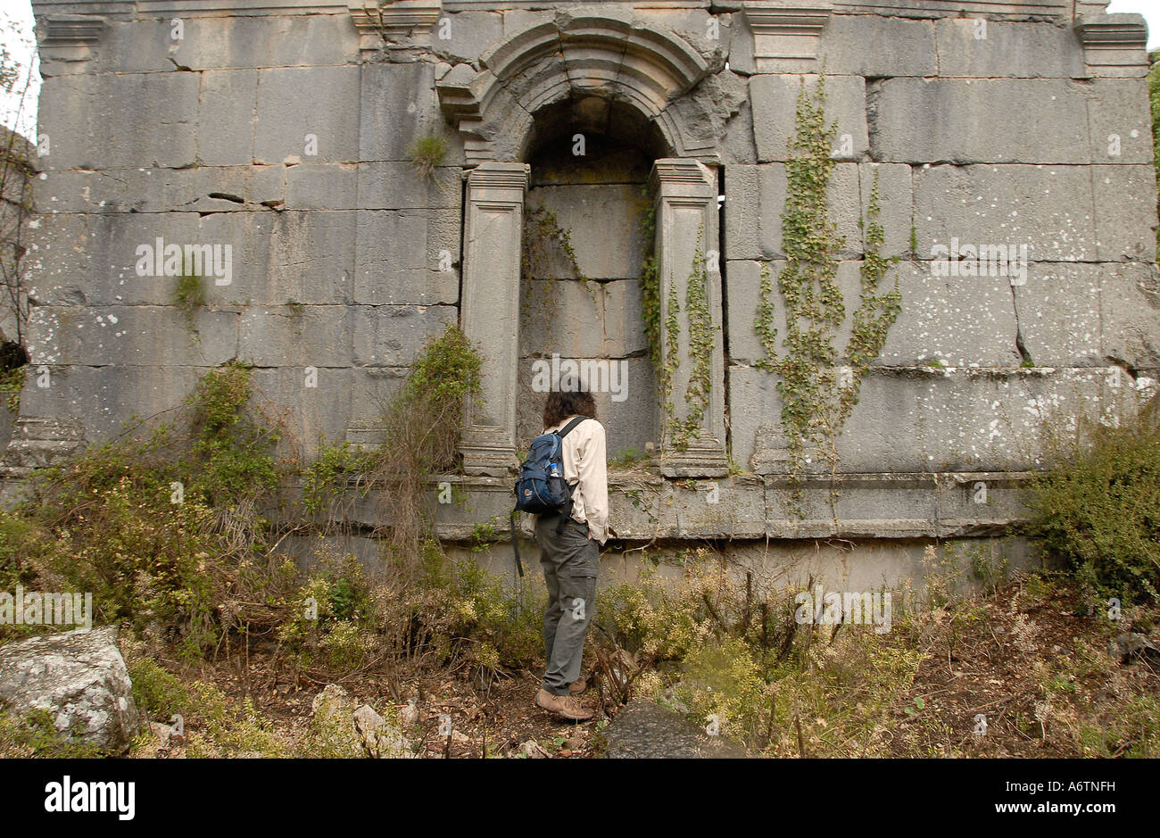 Ein junger Tourist steht inmitten alter Ruinen in Termessos oder Thermessos im Taurusgebirge, Provinz Antalya, Türkei Stockfoto