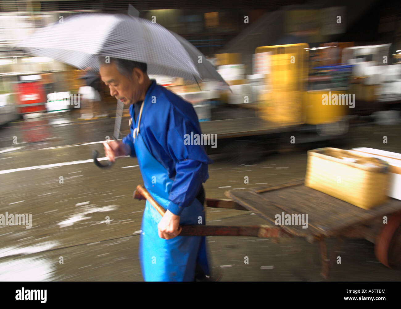 Japan zentralen Honshu Tokio Tsukiji Fischmarkt Fischhändler einen hölzernen Wagen ziehen und halten einen Regenschirm Stockfoto