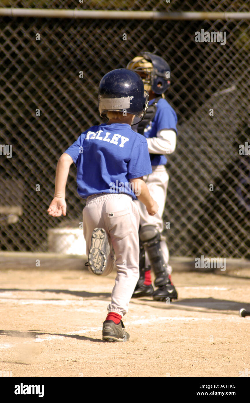 Jungen Alter 6 7 spielen kleine Liga Baseball-Jugend laufen in Richtung Heimatbasis Stockfoto