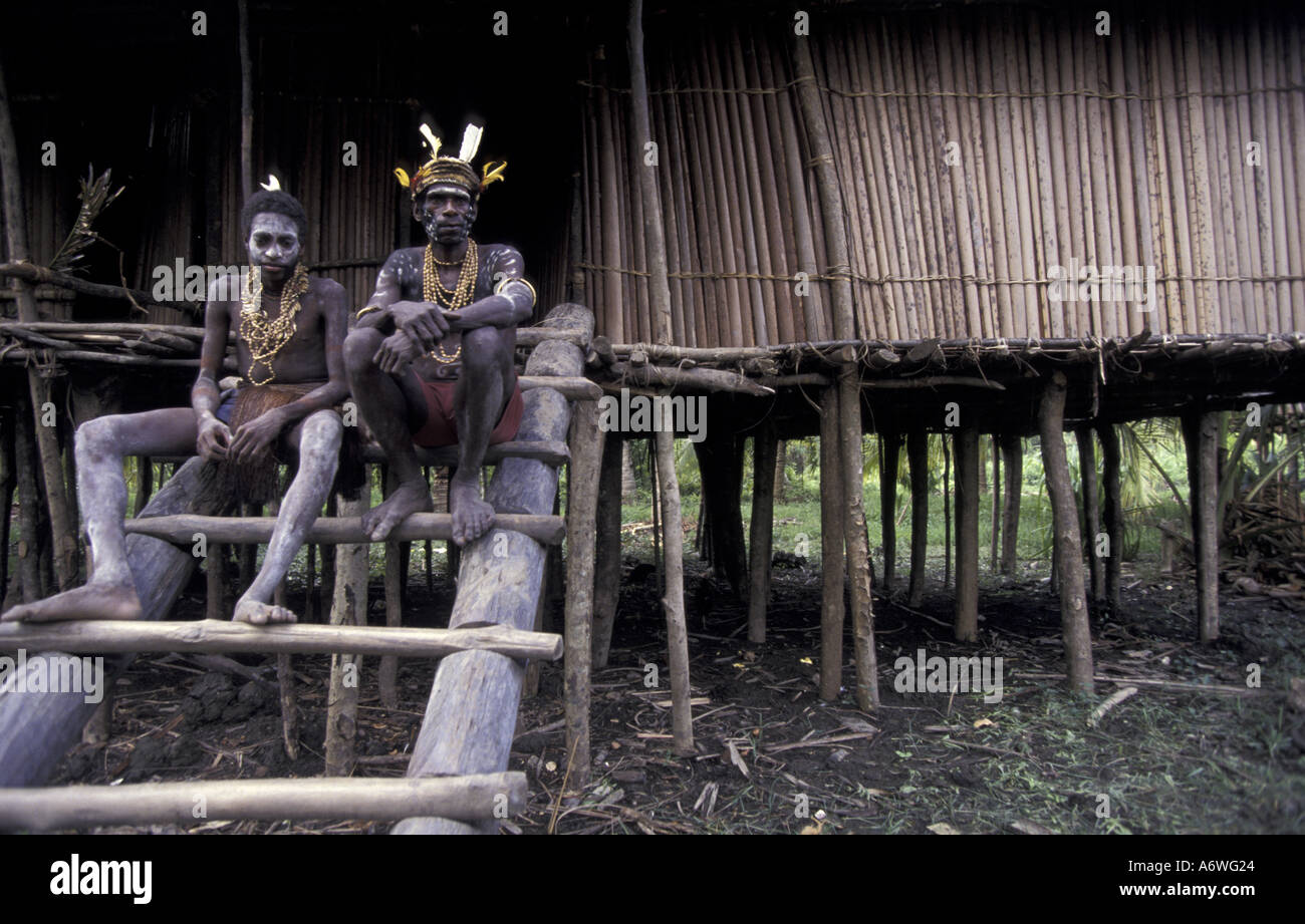 Asien, Indonesien, West Papua (Irian Jaya), Asmat Region. Männer sitzen auf Langhaus Leiter Stockfoto