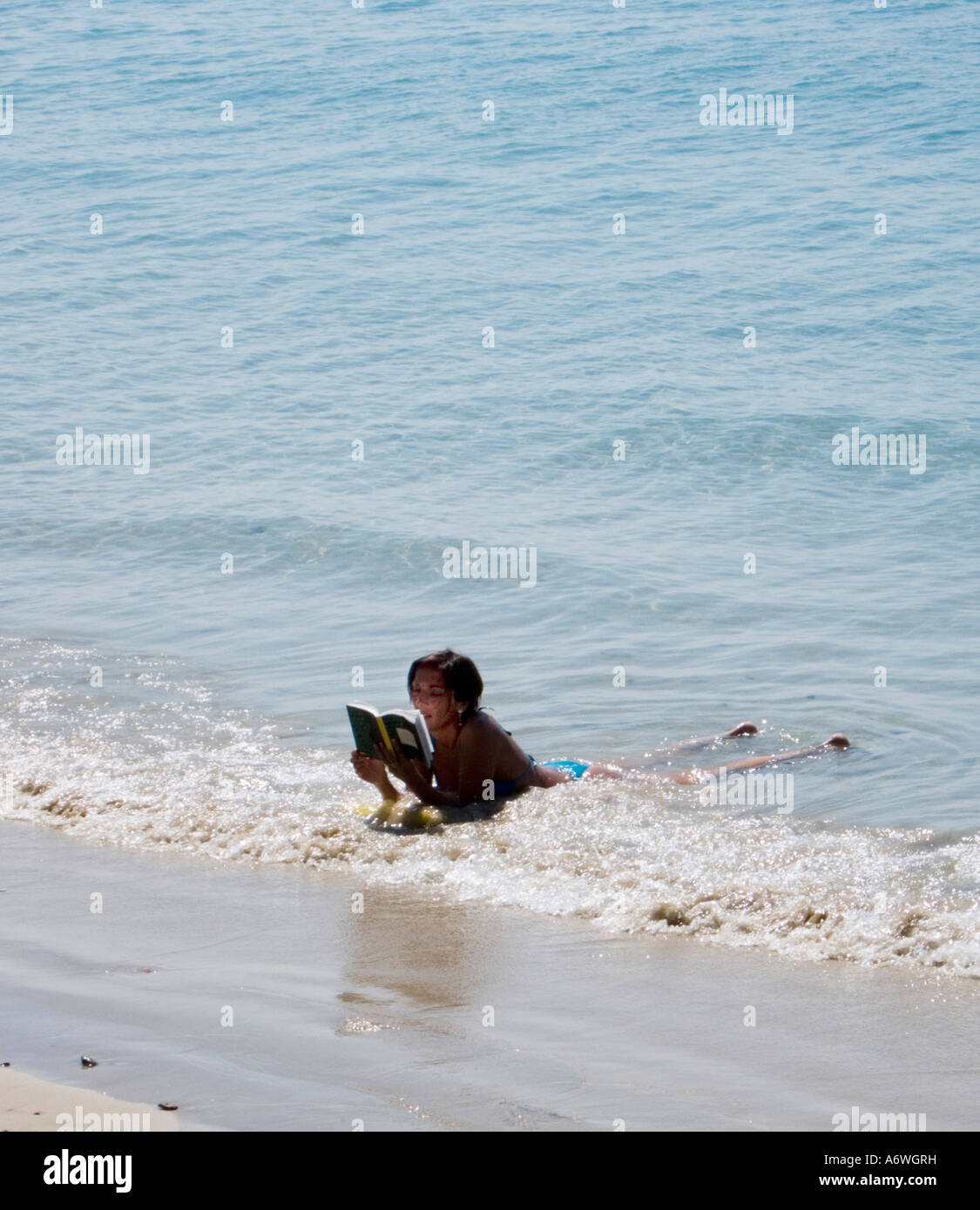 Eine Frau liegt im Rand Wassers Lesen eines Buches in Ao Nang in Krabi in Thailand Stockfoto
