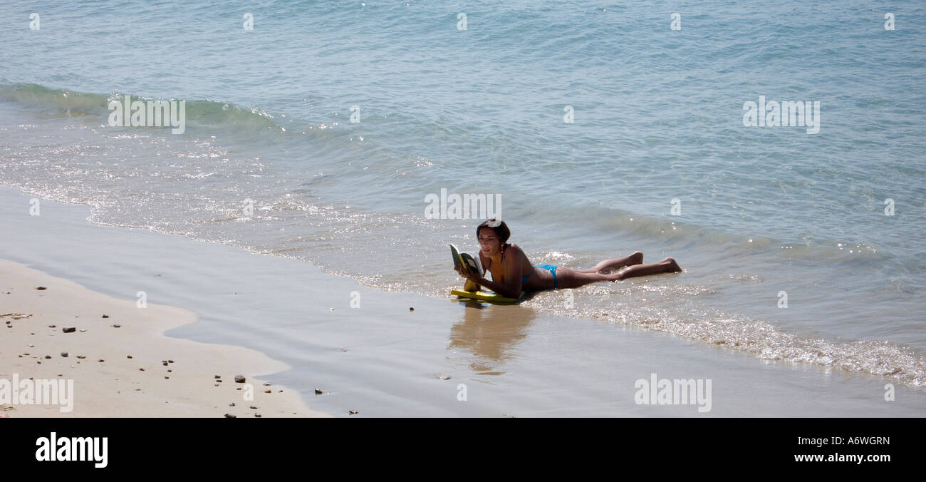 Eine Frau liegt im Rand Wassers Lesen eines Buches in Ao Nang in Krabi in Thailand Stockfoto