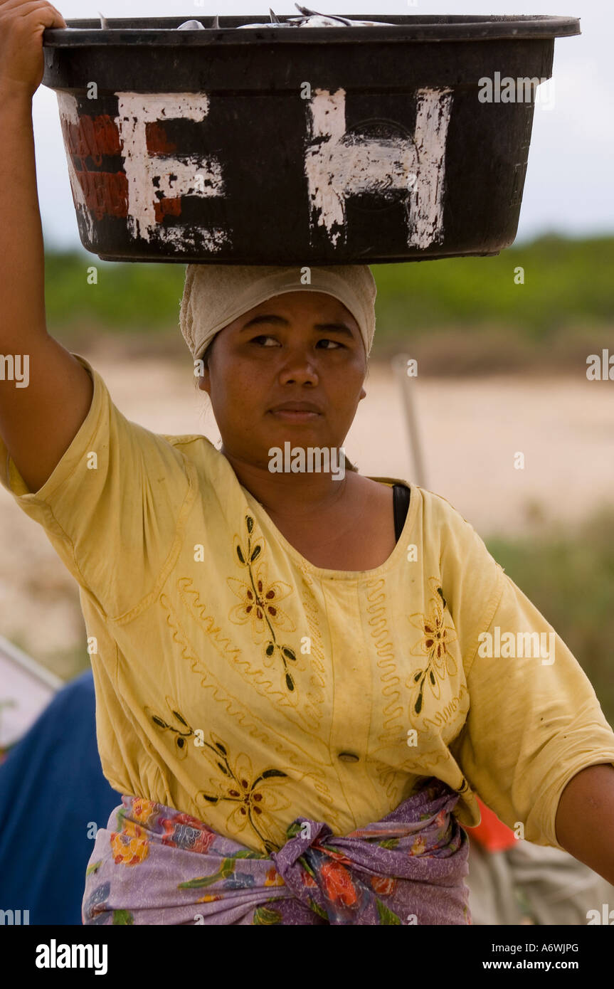 Frau, die Container voll mit Fisch auf dem Kopf trägt Stockfoto