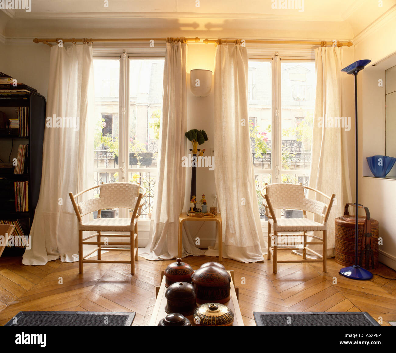 Stühle mit weißen sitzen und Holzrahmen vor hohen Doppelfenster mit weißen  Vorhängen im Wohnzimmer mit Parkettboden Stockfotografie - Alamy