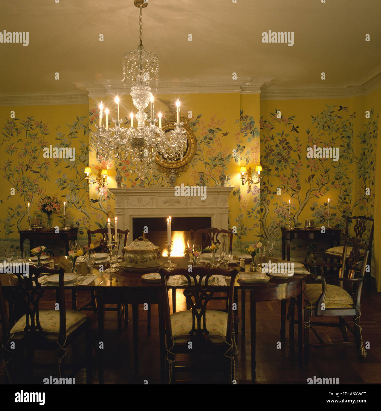 Glas-Kronleuchter über dem Tisch im Esszimmer mit gelb gemusterten Chinoiserie-Tapete Stockfoto