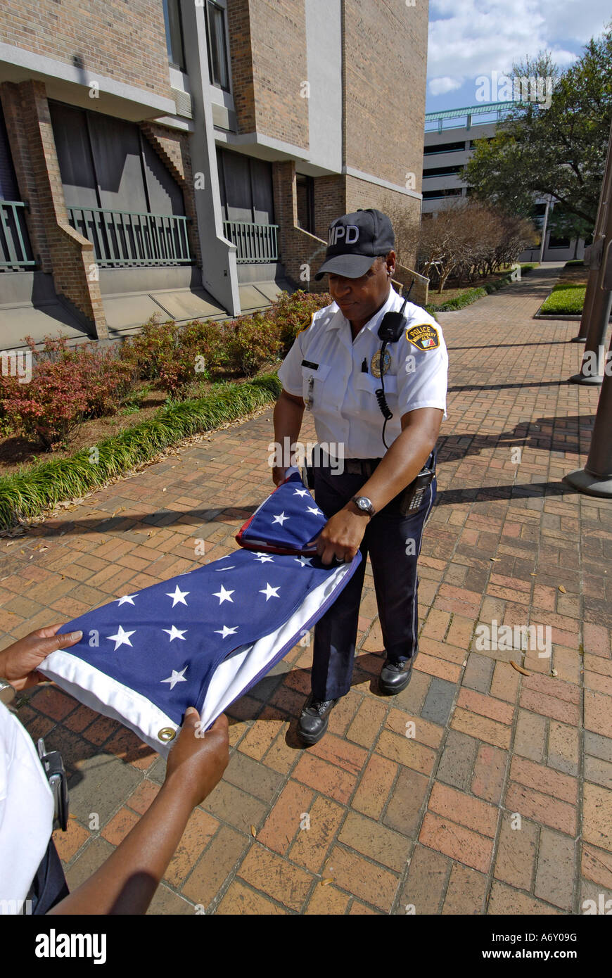 Schwarze weibliche Polizisten nehmen die Amerika Flagge eine Falte es am Ende des Tages in Montgomery Alabama AL Stockfoto