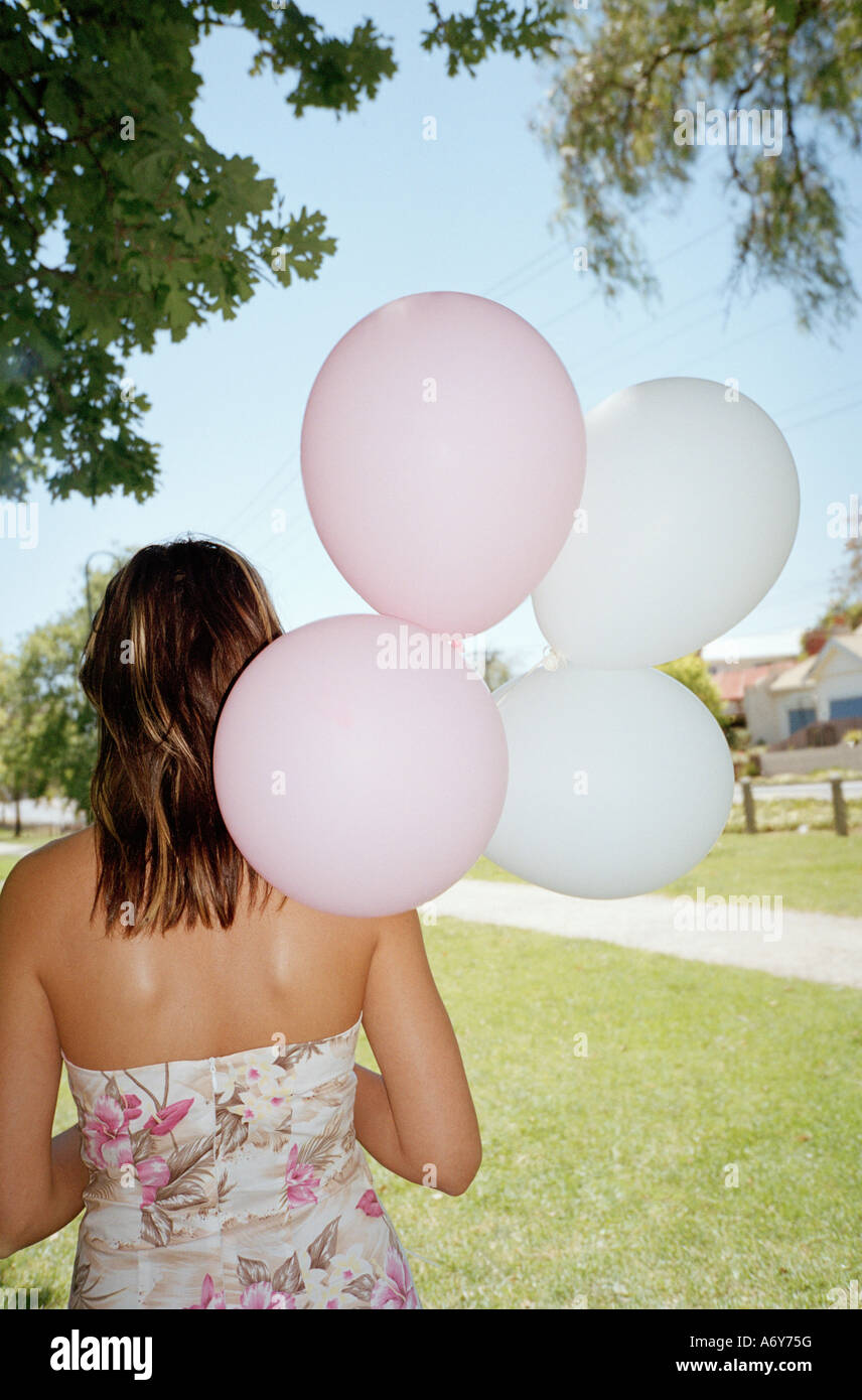 Frau stehend in einem Park und halten eine Reihe von Ballons Stockfoto