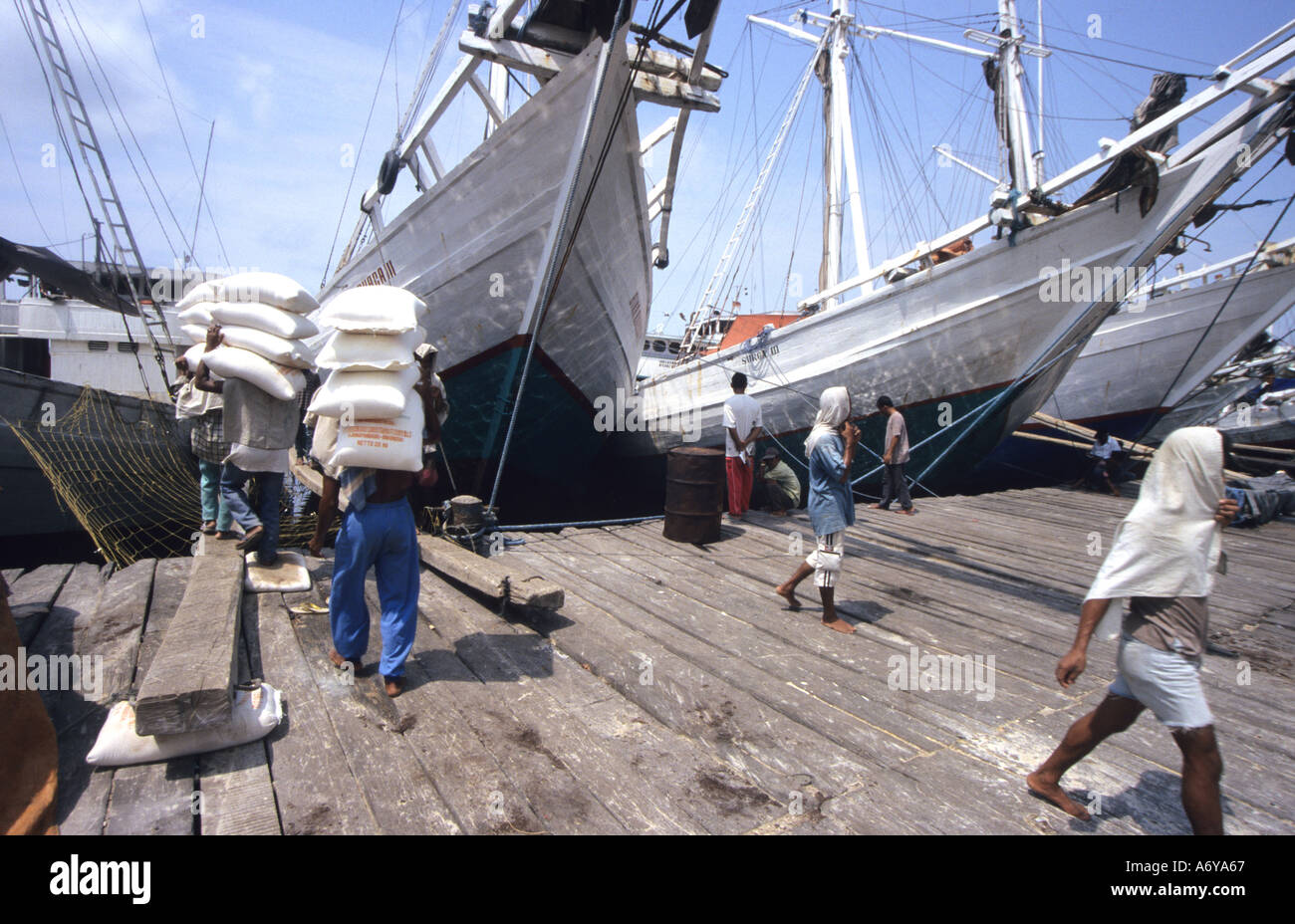 Porters Tragetaschen Reis laden ein "Bugis Boot" in einem Hafen in Jakarta, Indonesien Stockfoto